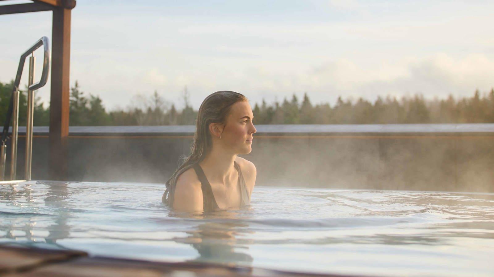 A guest in a steaming outdoor pool at The Well
