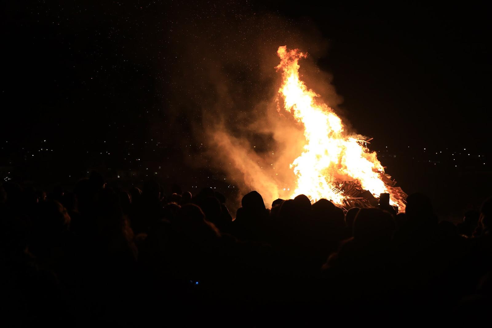 Crowd silhouetted against a large bonfire at night